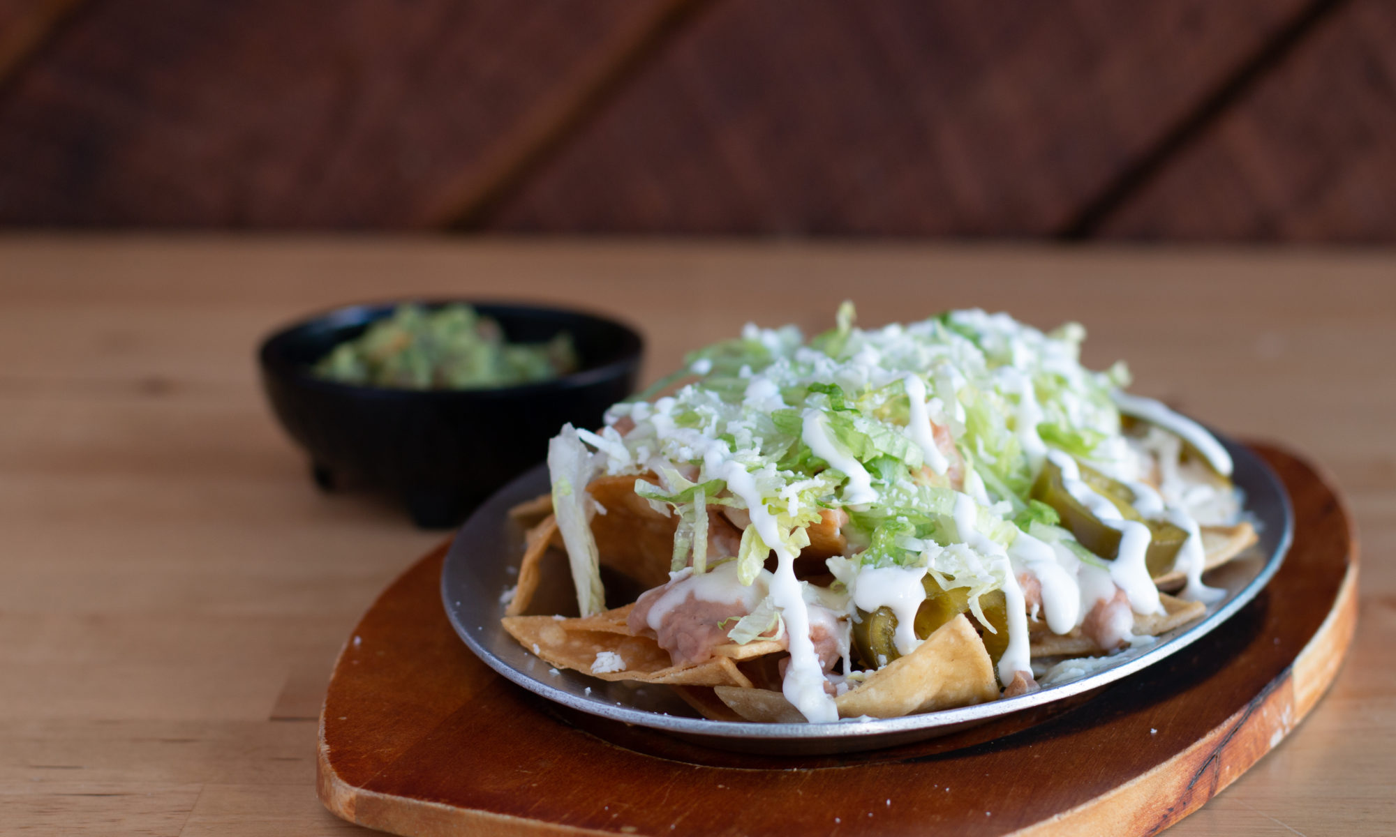 Super nachos with lettuce, crema and jalapeños, guacamole behind